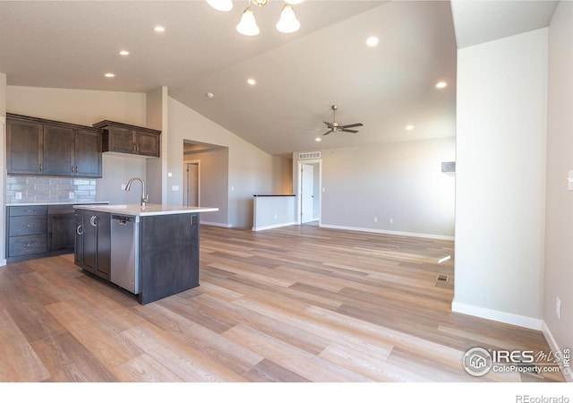 kitchen featuring a kitchen island with sink, dark brown cabinets, stainless steel dishwasher, light countertops, and light wood finished floors