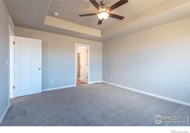 unfurnished bedroom featuring ceiling fan, carpet, baseboards, and a raised ceiling