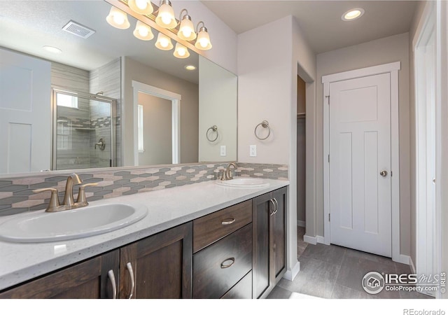 bathroom featuring double vanity, a stall shower, a sink, and visible vents