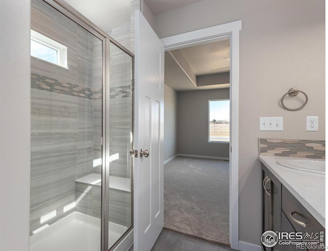 bathroom with a shower stall, baseboards, and vanity