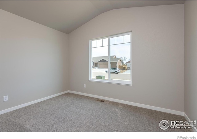 empty room with carpet, visible vents, vaulted ceiling, and baseboards