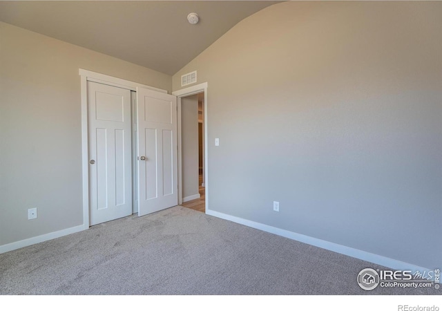 unfurnished bedroom with baseboards, visible vents, vaulted ceiling, carpet floors, and a closet