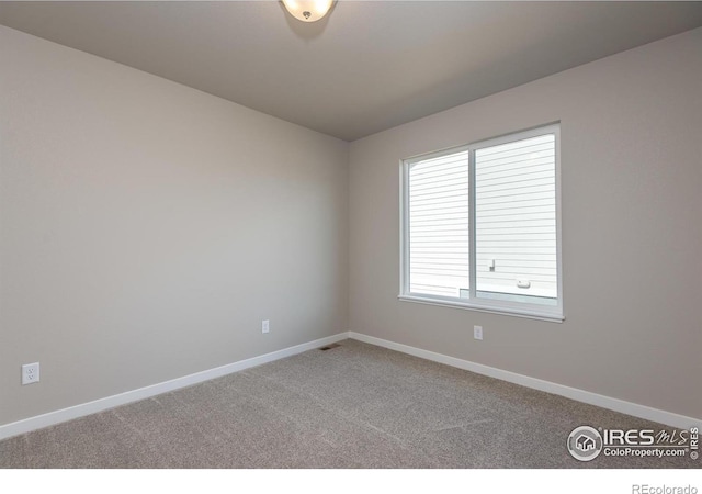 carpeted spare room featuring visible vents and baseboards