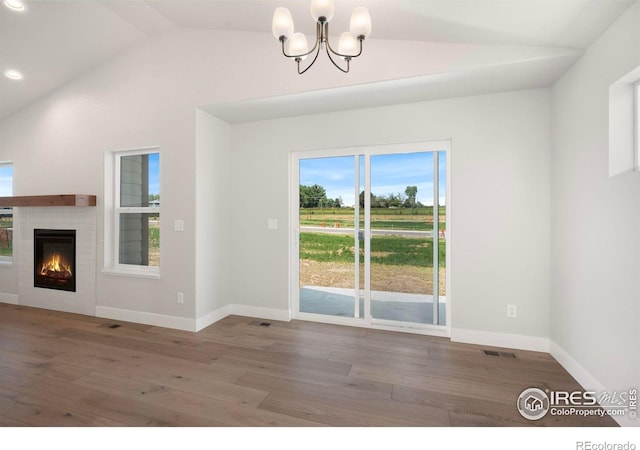 6997 Feather Reed Dr, Wellington, CO 80549 - unfurnished living room with vaulted ceiling, a chandelier, wood finished floors, a lit fireplace, and recessed lighting