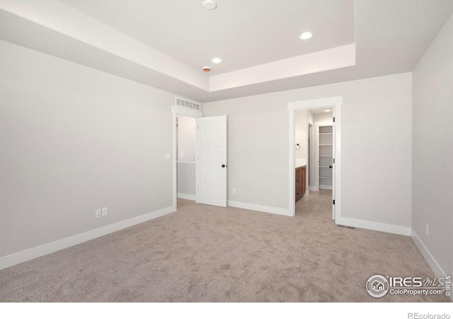 6997 Feather Reed Dr, Wellington, CO 80549 - unfurnished bedroom featuring light colored carpet, recessed lighting, a tray ceiling, and ensuite bathroom