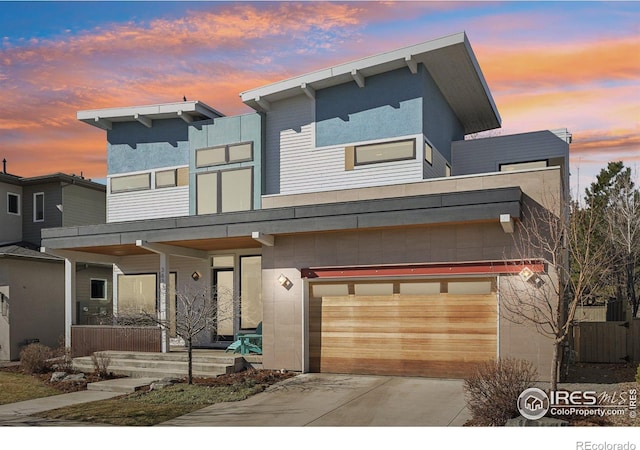 contemporary house featuring covered porch, concrete driveway, and an attached garage