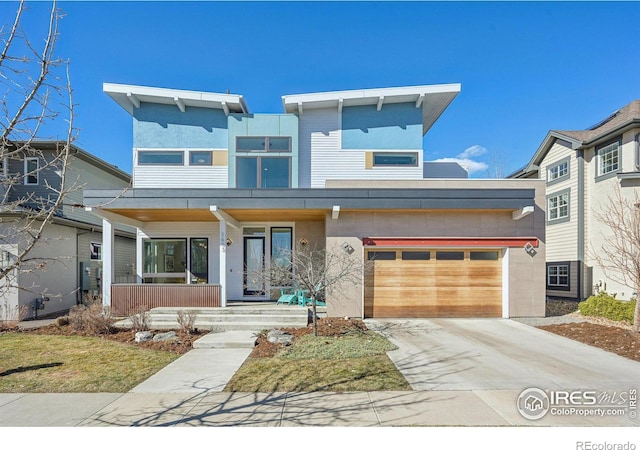 contemporary home with a porch, concrete driveway, an attached garage, and stucco siding