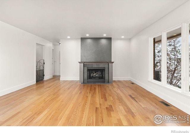 unfurnished living room featuring a tile fireplace, recessed lighting, visible vents, baseboards, and light wood-type flooring