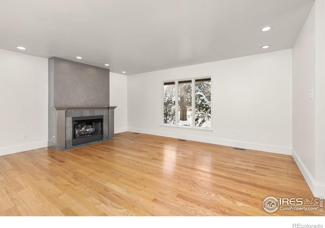 unfurnished living room with a fireplace, recessed lighting, visible vents, wood finished floors, and baseboards