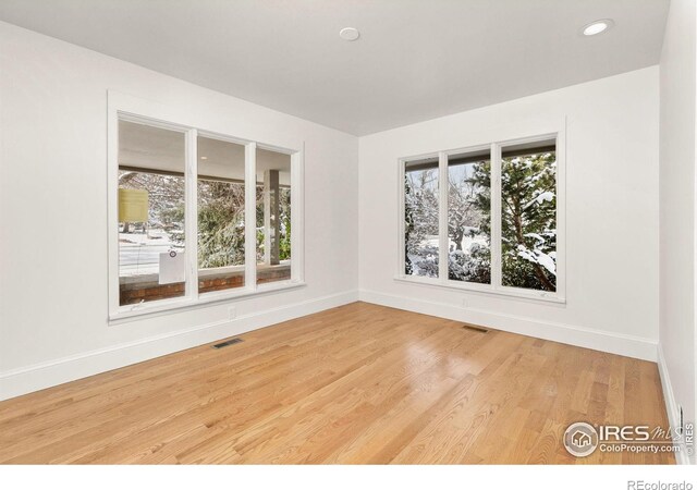 unfurnished room featuring light wood-style flooring, visible vents, and baseboards