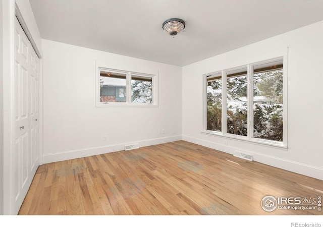 unfurnished bedroom with light wood-type flooring, visible vents, and baseboards