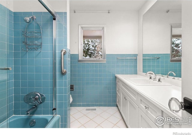 full bath with tile patterned flooring, a wainscoted wall, vanity, tile walls, and shower / washtub combination