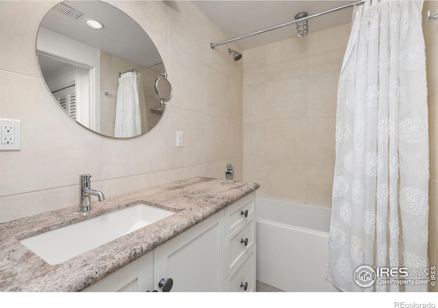 bathroom featuring tile walls, visible vents, shower / tub combo with curtain, and vanity