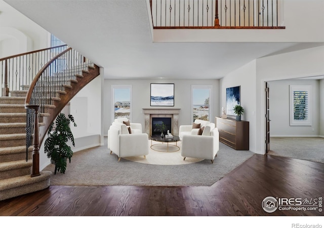 living room featuring stairs, a premium fireplace, wood finished floors, and baseboards