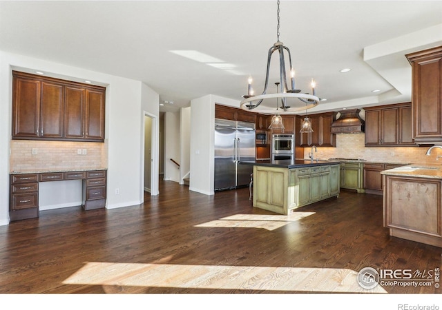 kitchen with custom range hood, appliances with stainless steel finishes, dark wood-type flooring, and a center island with sink