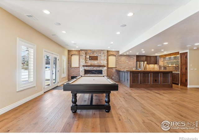 rec room with a stone fireplace, light wood-style flooring, recessed lighting, baseboards, and french doors