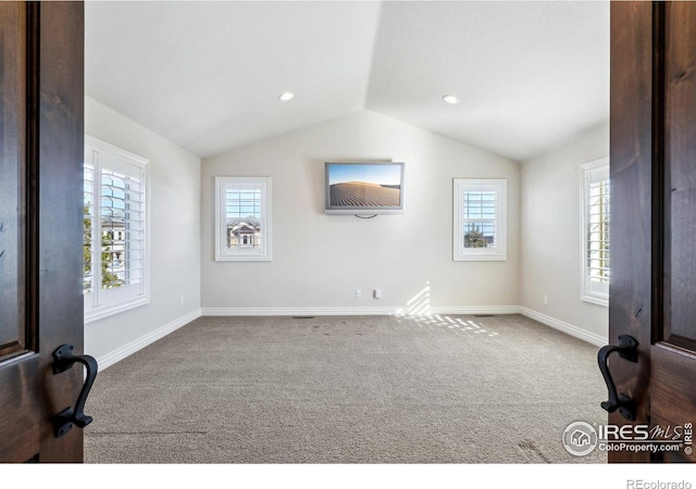 interior space with lofted ceiling, baseboards, carpet flooring, and a healthy amount of sunlight