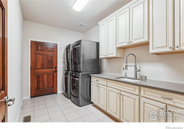 kitchen with visible vents, a sink, stacked washing maching and dryer, and light tile patterned floors