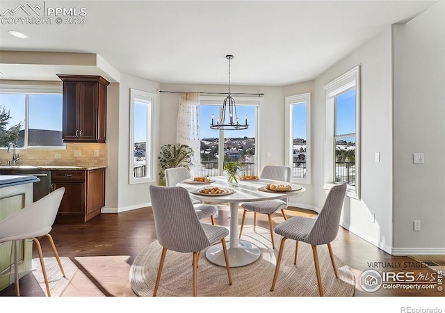 dining space featuring dark wood finished floors, a chandelier, healthy amount of natural light, and baseboards
