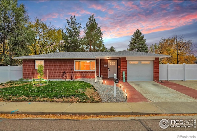 ranch-style home featuring brick siding, concrete driveway, a lawn, fence, and a garage