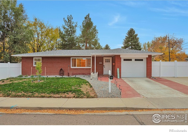 ranch-style home with a garage, brick siding, fence, concrete driveway, and a front yard