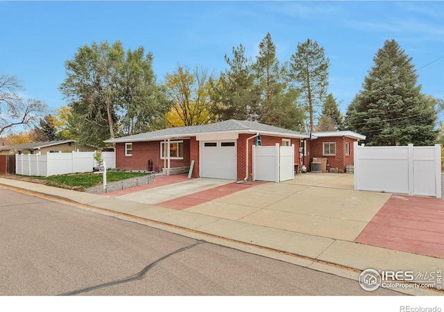 single story home with concrete driveway, brick siding, an attached garage, and fence