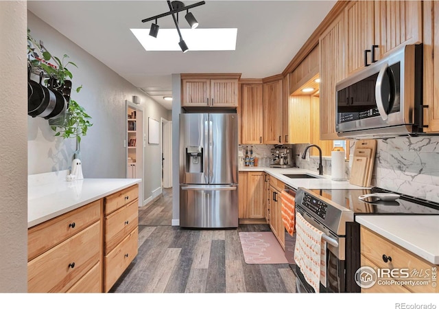 kitchen featuring dark wood-style floors, tasteful backsplash, light countertops, appliances with stainless steel finishes, and a sink