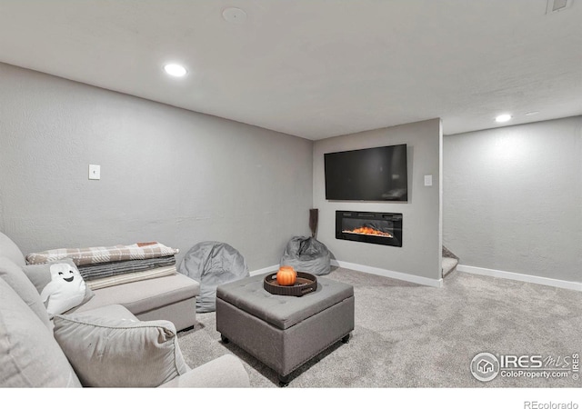 carpeted living room with a glass covered fireplace, baseboards, and recessed lighting