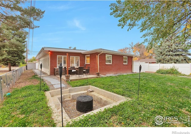 rear view of house with a yard, brick siding, a patio, and a fenced backyard