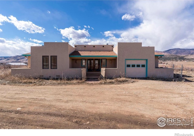 view of front of property featuring an attached garage, driveway, a mountain view, and stucco siding