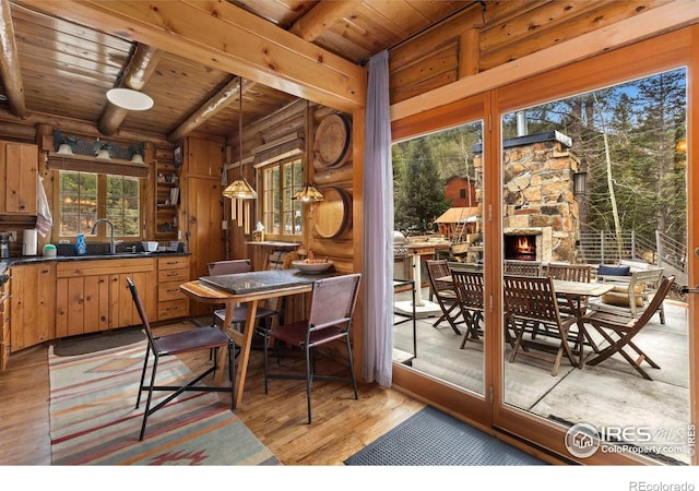 dining space with light wood finished floors, wooden ceiling, beam ceiling, and a healthy amount of sunlight