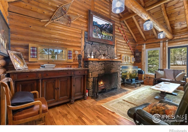 living area with beam ceiling, light wood-type flooring, log walls, wood ceiling, and a stone fireplace