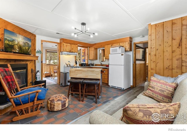 living area featuring dark wood finished floors, visible vents, a notable chandelier, wooden walls, and a fireplace