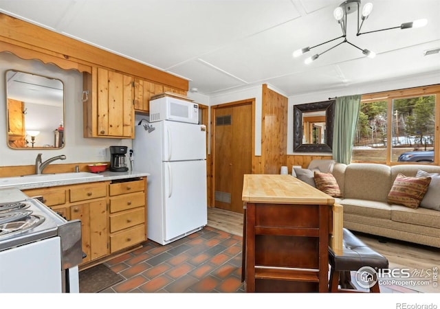 kitchen with visible vents, open floor plan, a sink, and white appliances