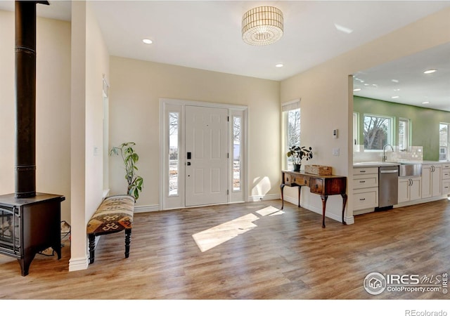 entrance foyer featuring recessed lighting, a wood stove, baseboards, and light wood finished floors