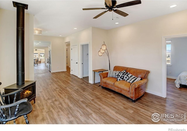 sitting room featuring baseboards, light wood-style flooring, a wood stove, and recessed lighting