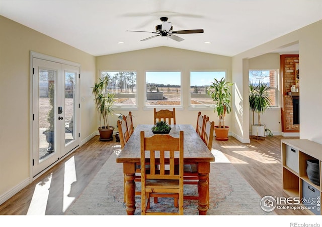 dining room featuring lofted ceiling, a healthy amount of sunlight, light wood-style flooring, and baseboards