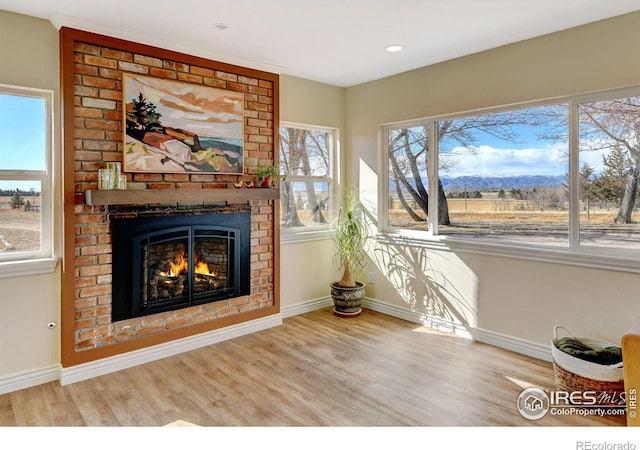 unfurnished living room with a fireplace, baseboards, and wood finished floors