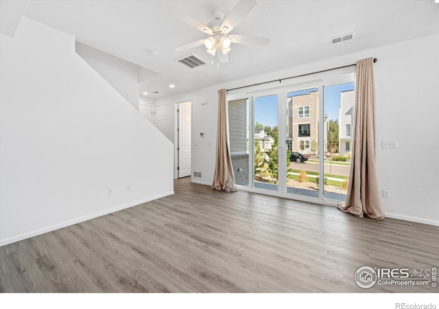 unfurnished living room featuring visible vents, baseboards, and wood finished floors