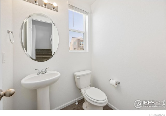 bathroom featuring baseboards, a sink, toilet, and wood finished floors