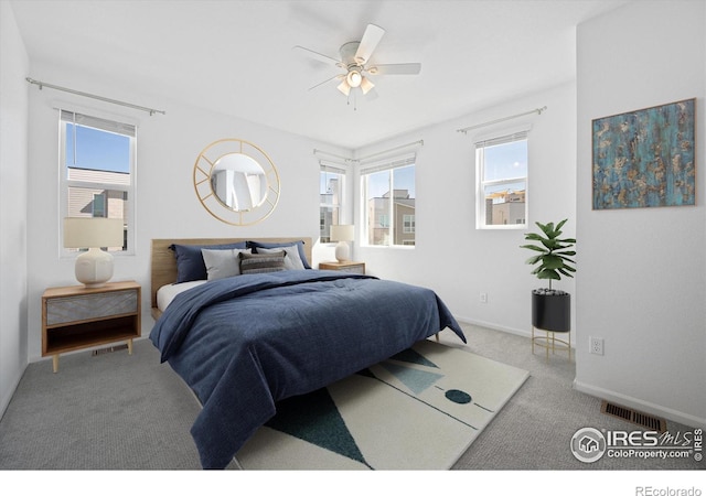 carpeted bedroom featuring a ceiling fan, visible vents, and baseboards