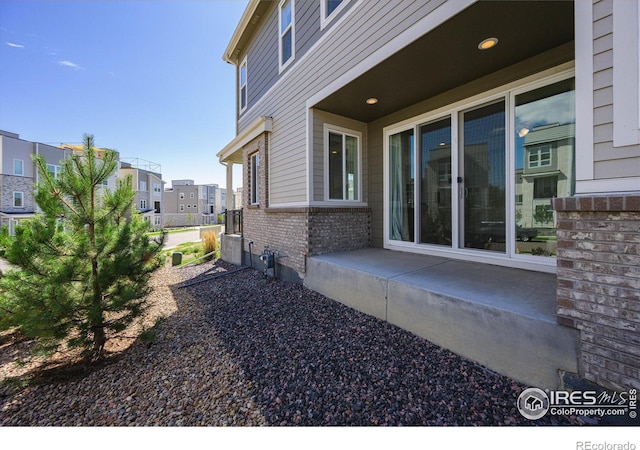 view of side of property with a patio, brick siding, and a residential view