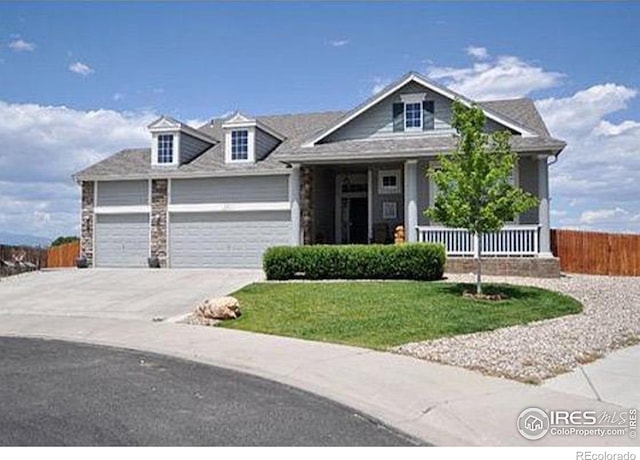 view of front of house with a porch, an attached garage, fence, concrete driveway, and a front yard