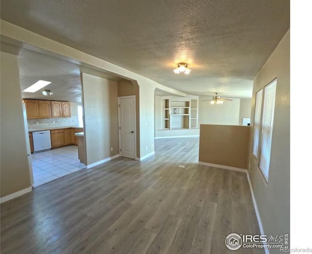 unfurnished living room with light wood-style floors, baseboards, and a textured ceiling