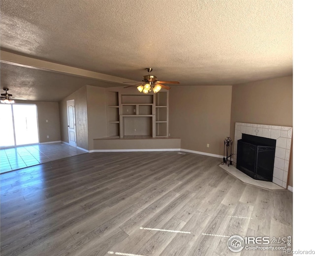 unfurnished living room with a textured ceiling, a tile fireplace, a ceiling fan, and light wood-style floors