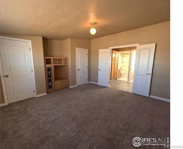 unfurnished bedroom with a textured ceiling, carpet, and baseboards