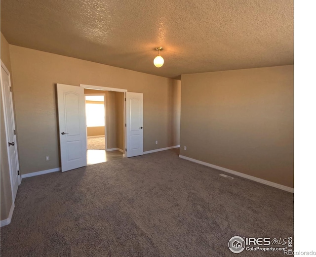 unfurnished bedroom with a textured ceiling, carpet, and baseboards