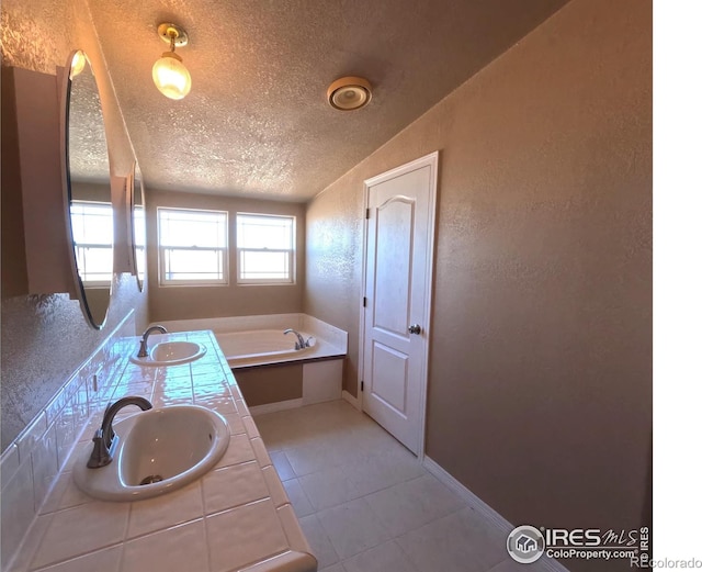 full bath featuring a textured wall, a sink, a textured ceiling, and a bath