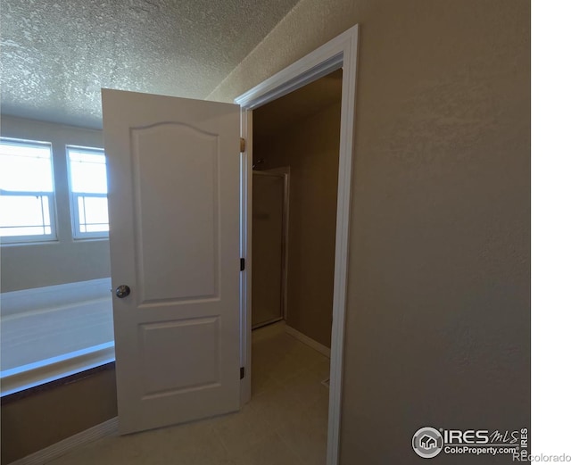 interior space featuring tile patterned flooring, a shower stall, and a textured ceiling