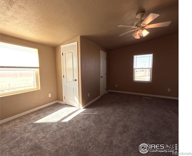 unfurnished bedroom featuring lofted ceiling, carpet, baseboards, and a textured ceiling